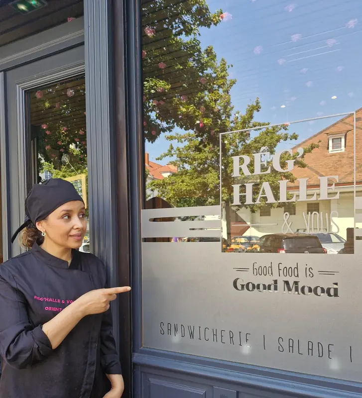Atika, la patronne de Rég'Halle & Vous, devant la vitrine de la boutique