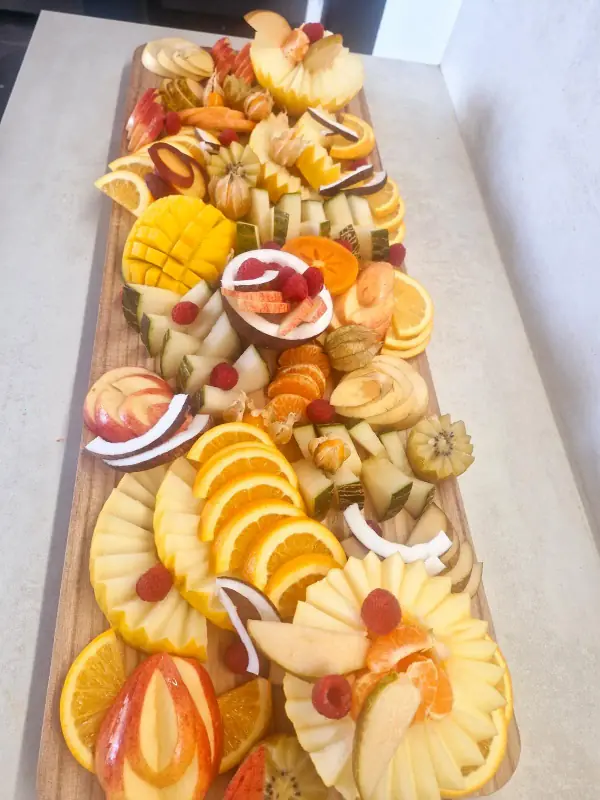 Long plateau de fruits frais découpés : mangue, oranges, melon et ananas